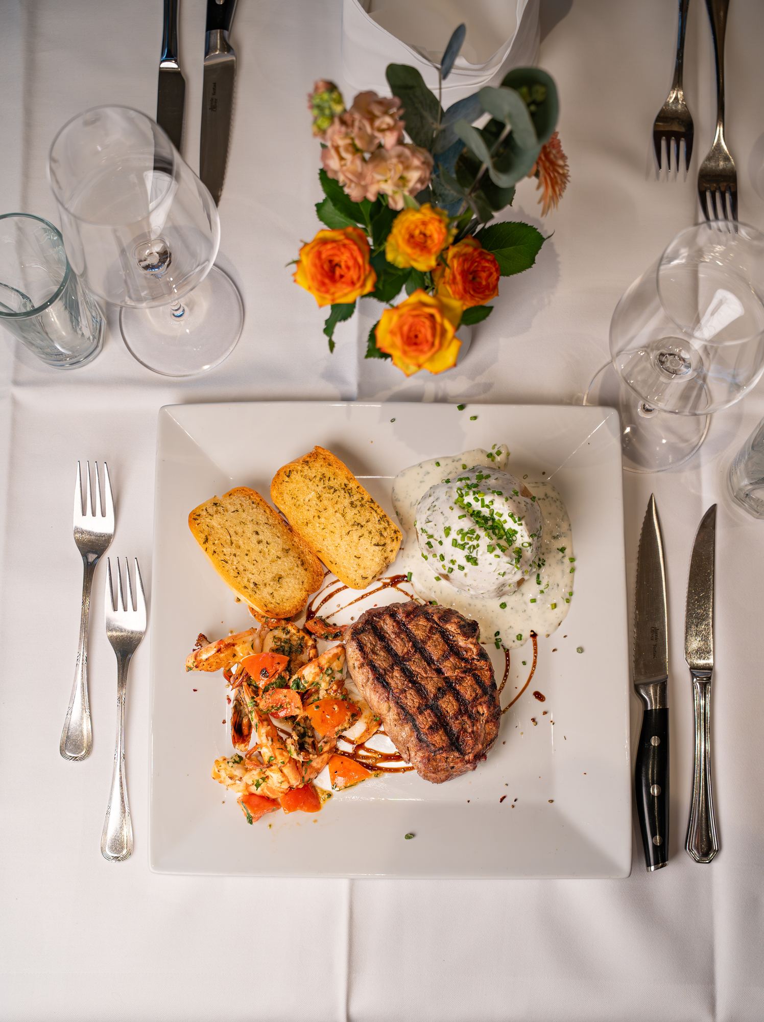 Grilled steak with prawns, potatoes and garlic bread